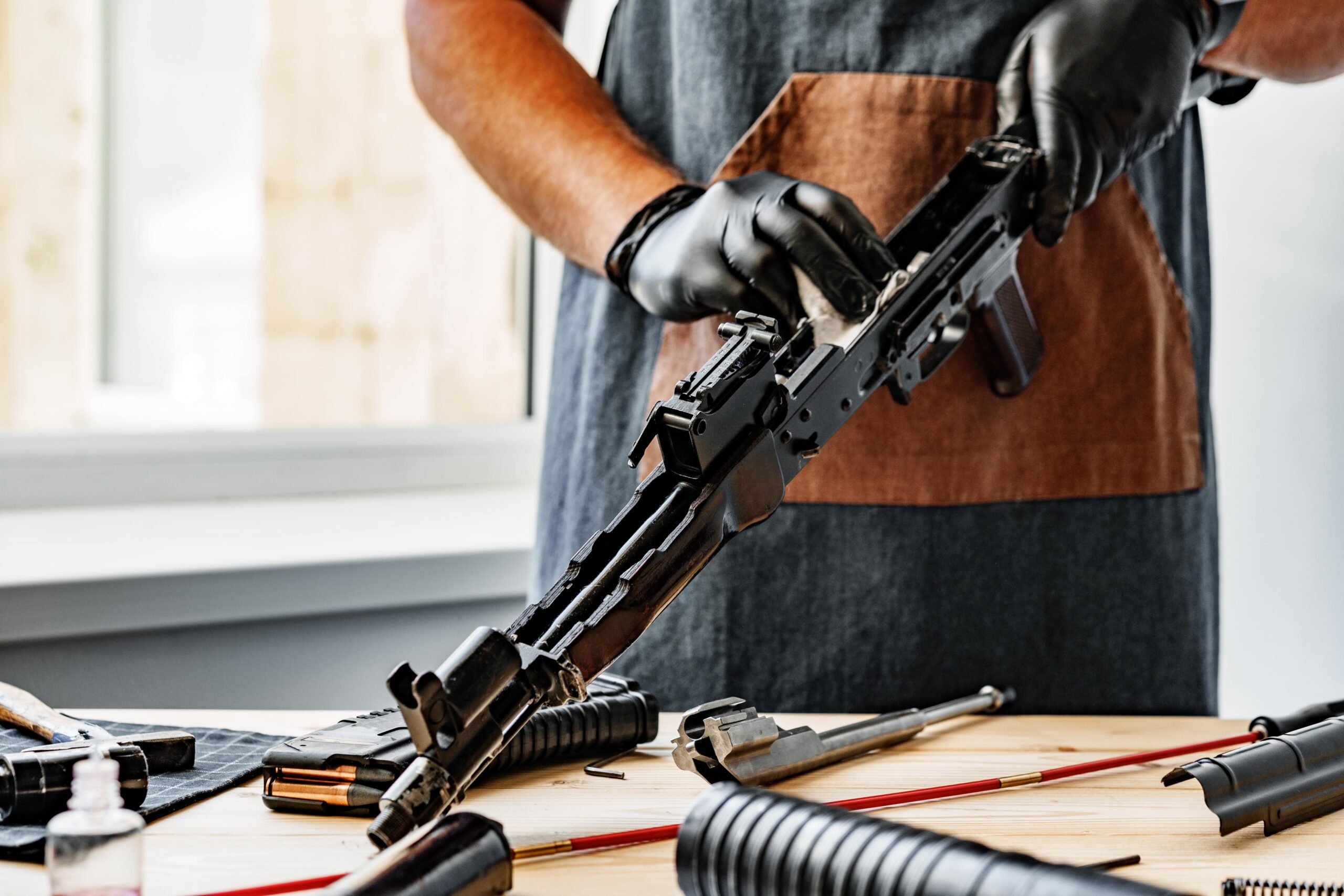 close-up-of-a-man-in-apron-wiping-his-firearm-with-2022-09-09-02-20-36-utc-min